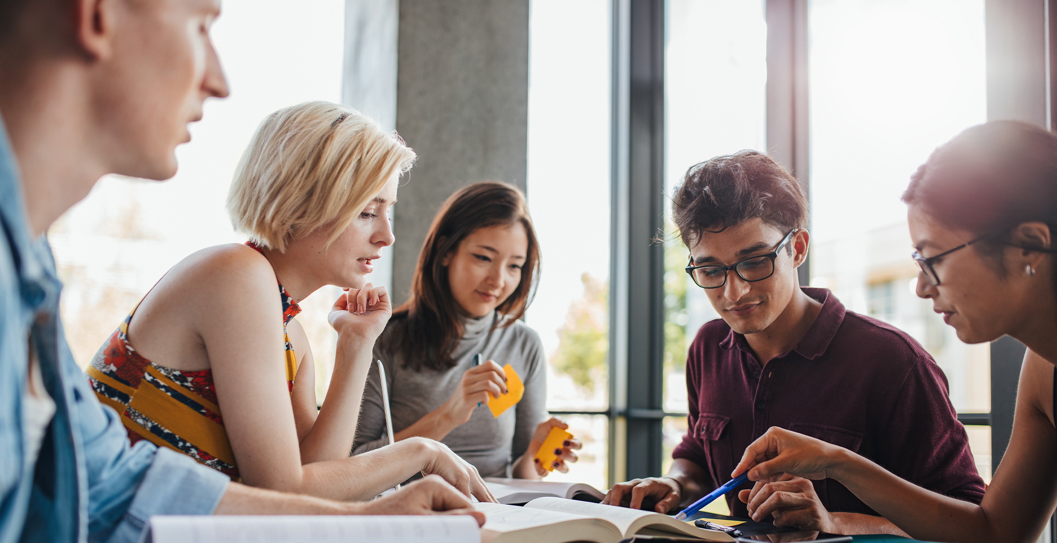 5 people talking and looking at books